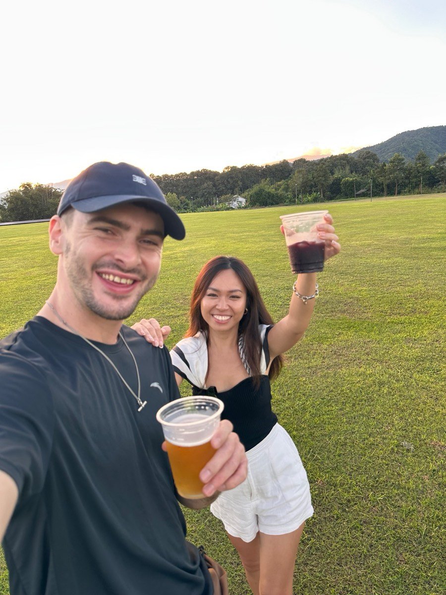 Oli and Vivi raising a drink on a sunny lawn